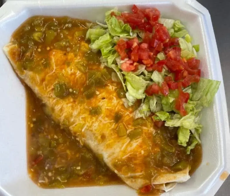 Burrito smothered in homemade green chili with lettuce and tomatoes