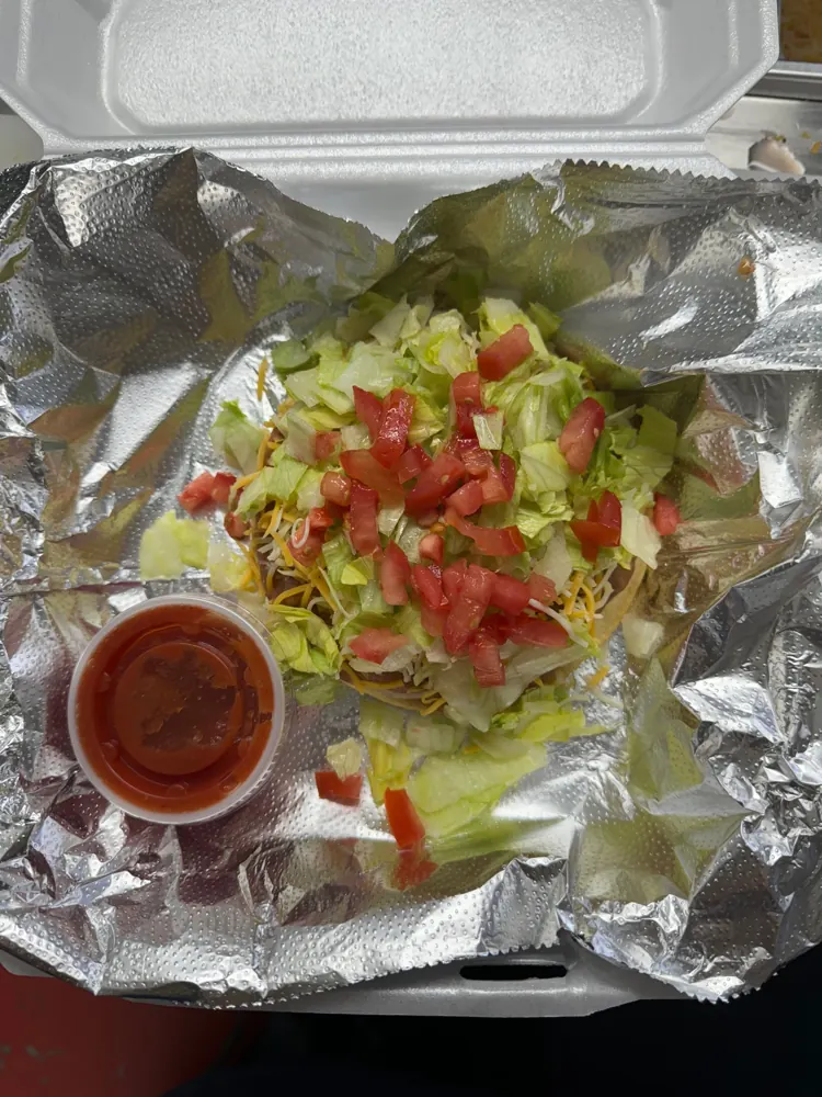 Tostada layered with beans, cheese, lettuce and tomato with salsa